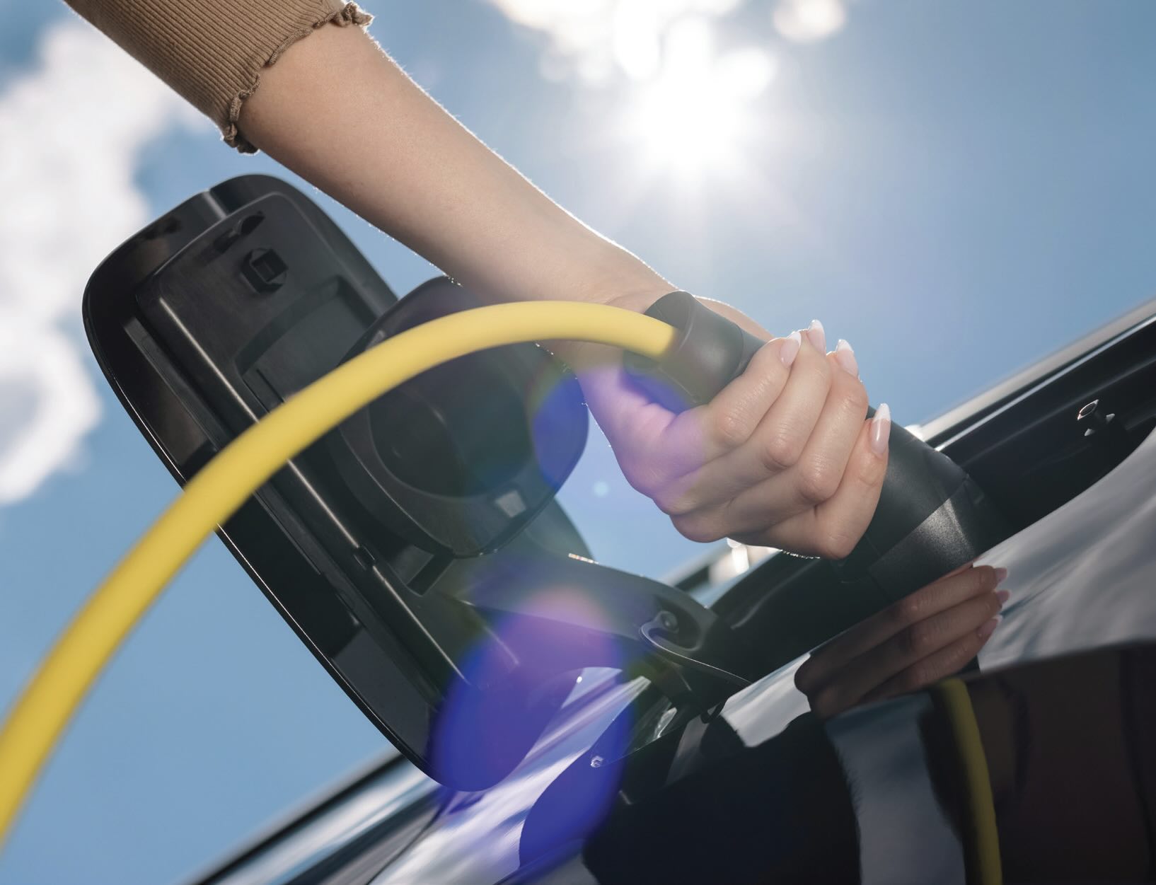 a hand plugging in an electric vehicle to charge