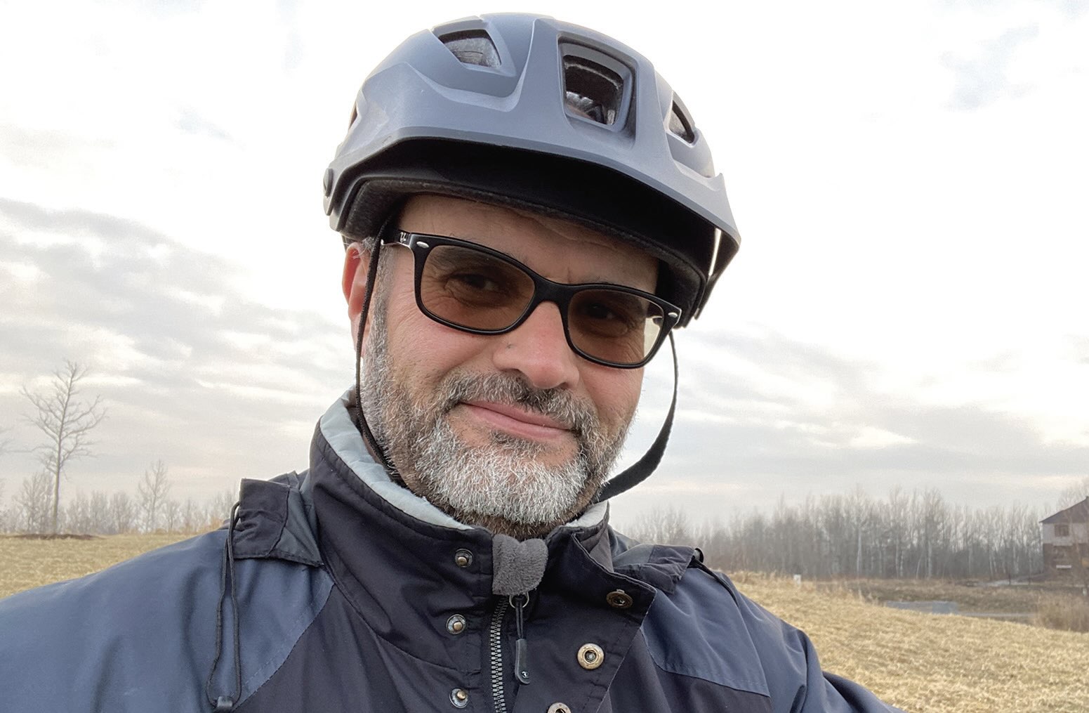 Photo of a man wearing sunglasses and a bike helmet
