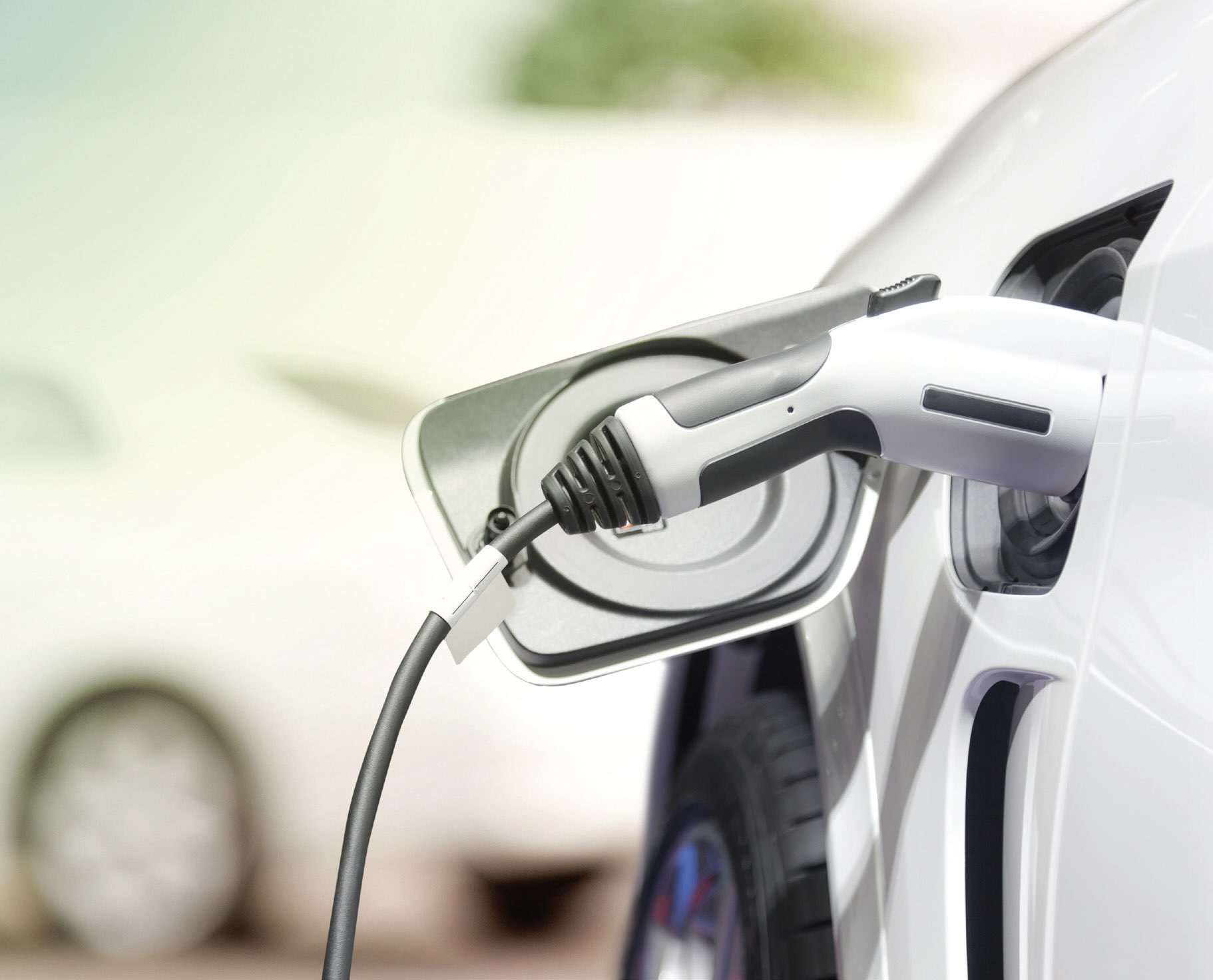 Close up view of a white electric vehicle plugged in for charging