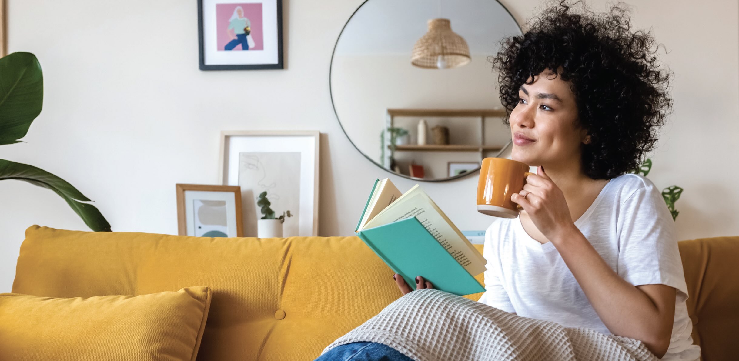 Photo of a smiling woman holding a coffee mug and a book