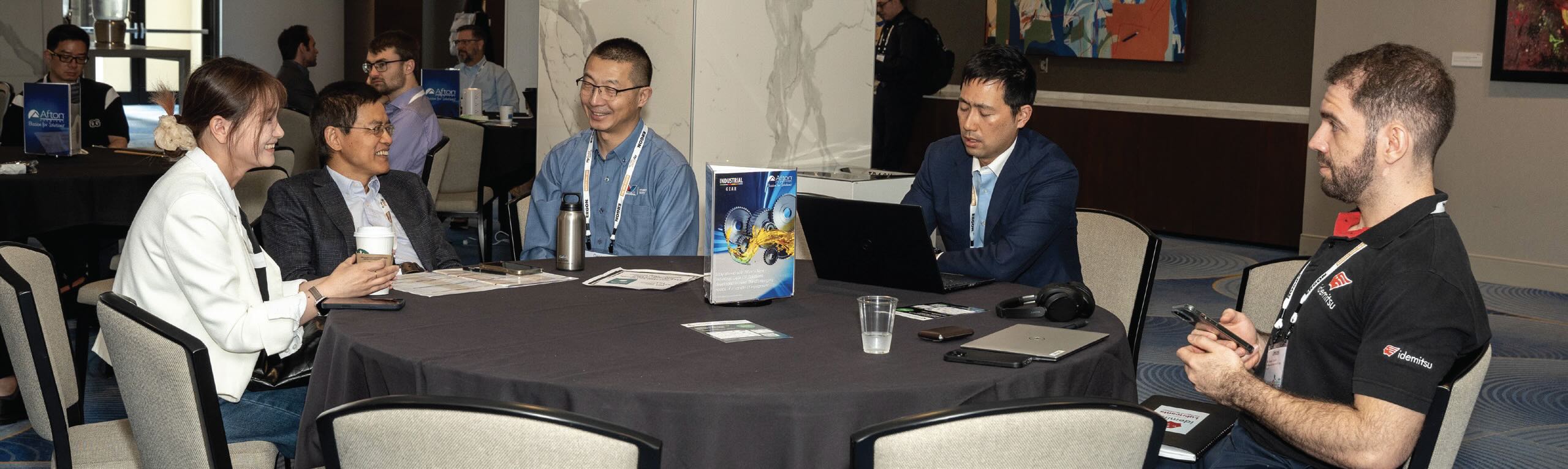 A group of smiling people sitting at a table during a conference.