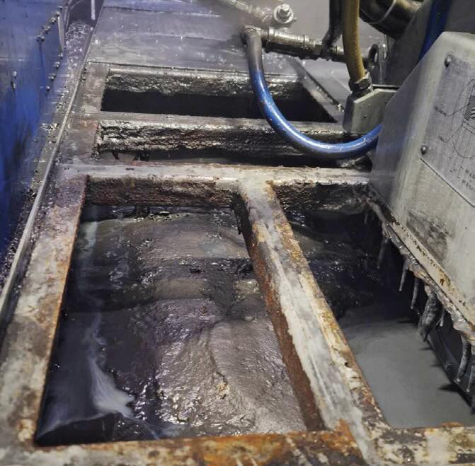 Coolant tank in mid-cleaning phase, showing accumulated sludge, tramp oil and sediment. This buildup reduces coolant efficiency and contributes to bacterial growth if not addressed through regular maintenance.