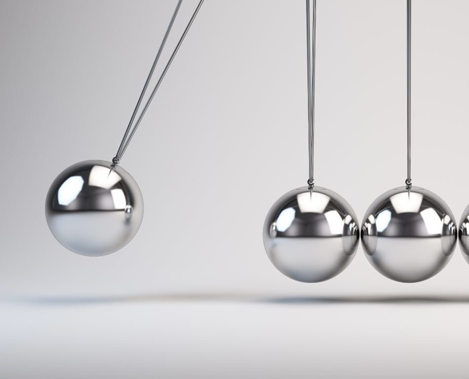 A silver ball swinging towards a line of more silver balls in demonstration of linear momentum