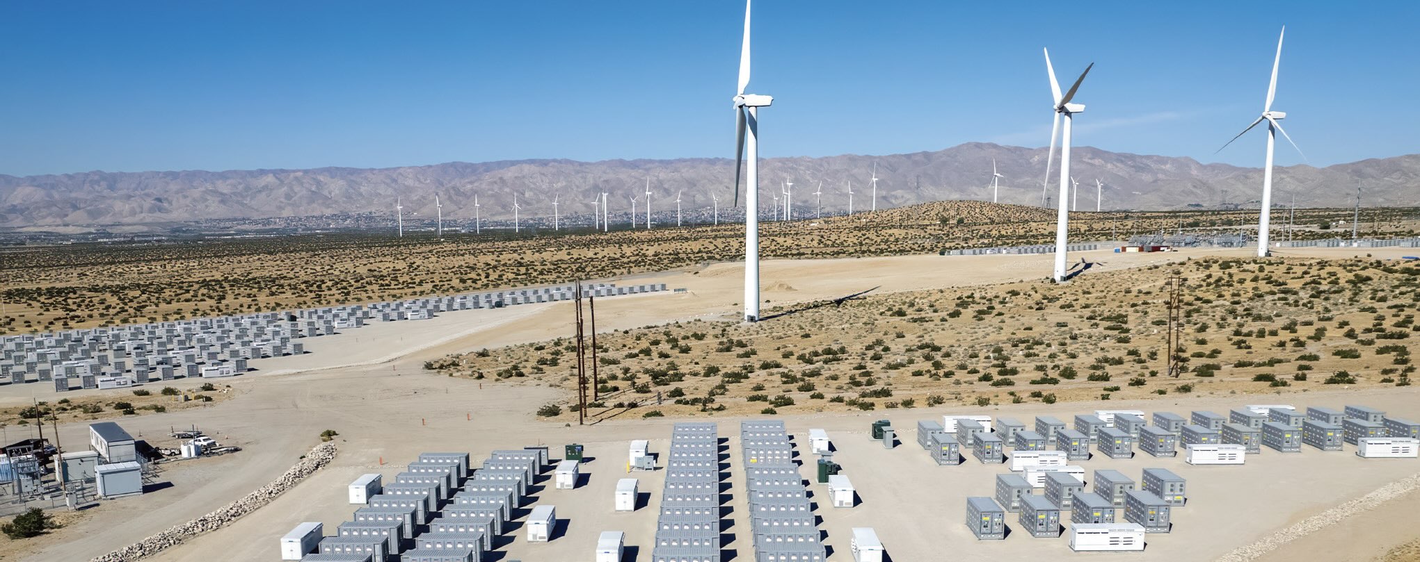 A field with wind turbines and energy storage