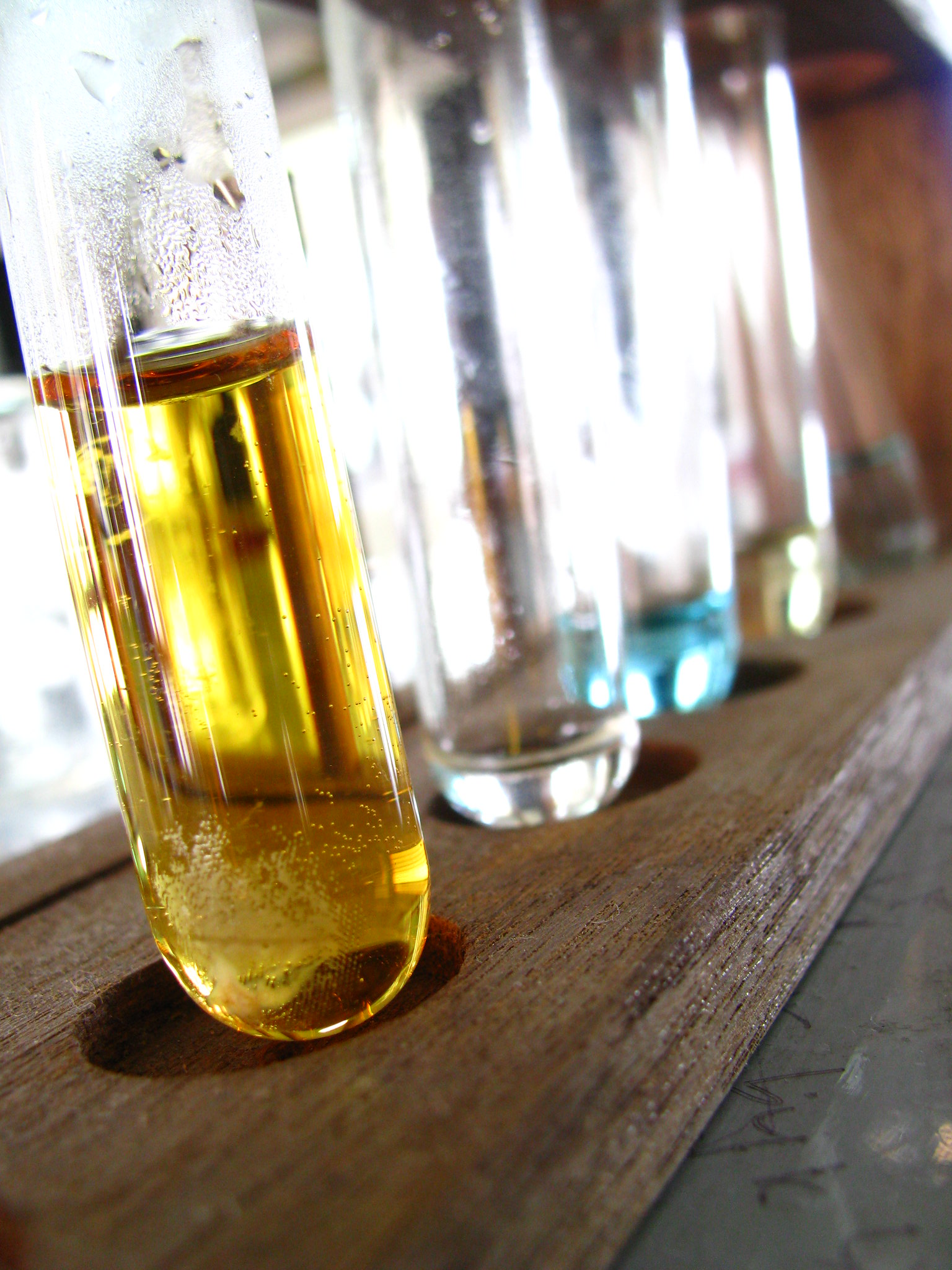 A test tube with golden liquid and other test tubes in the background.