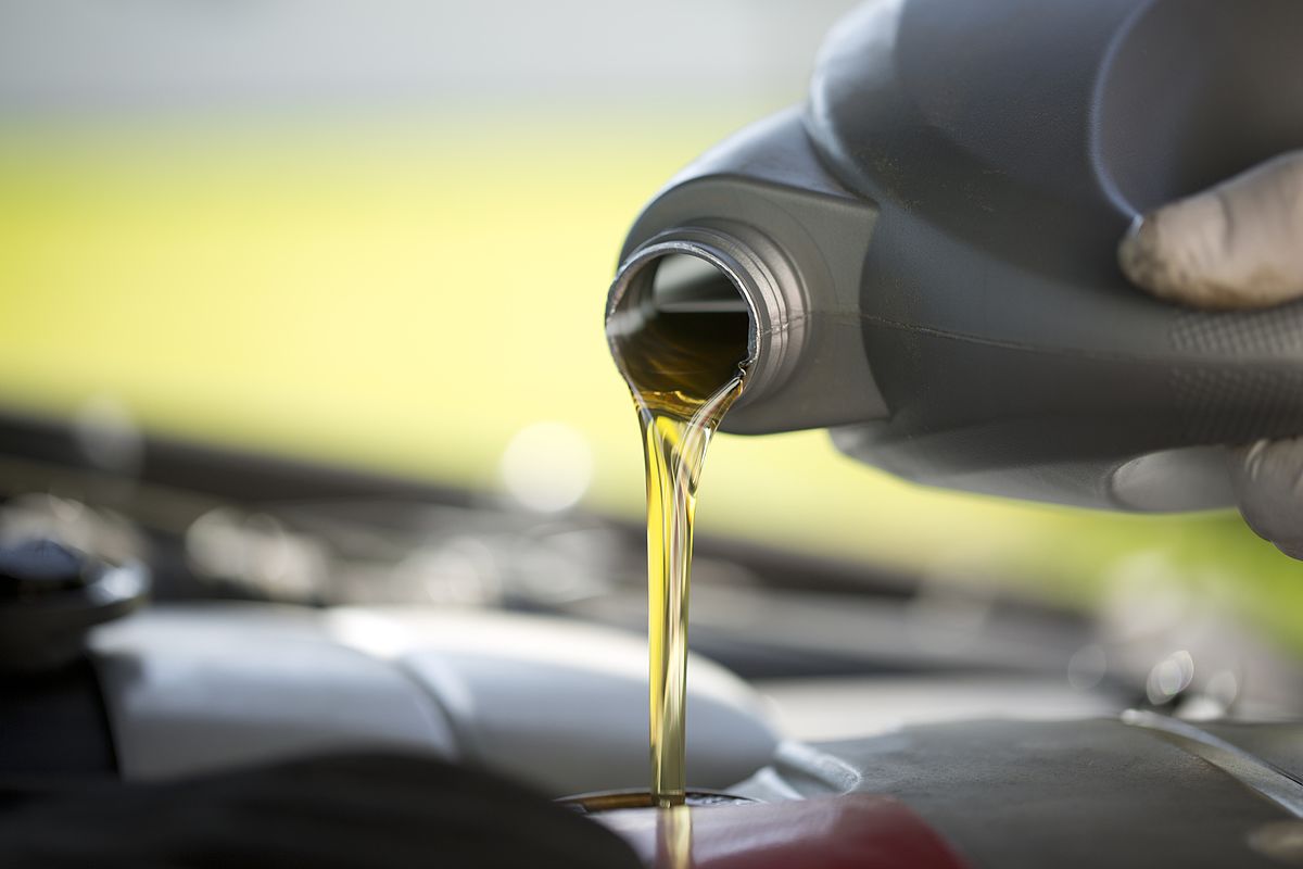 A photo of golden oil pouring from a black bottle.
