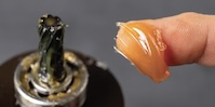 A photo of some grease on a fingertip, ready to apply to machinery.