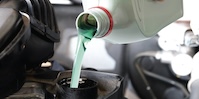 Green liquid pouring from a white bottle.